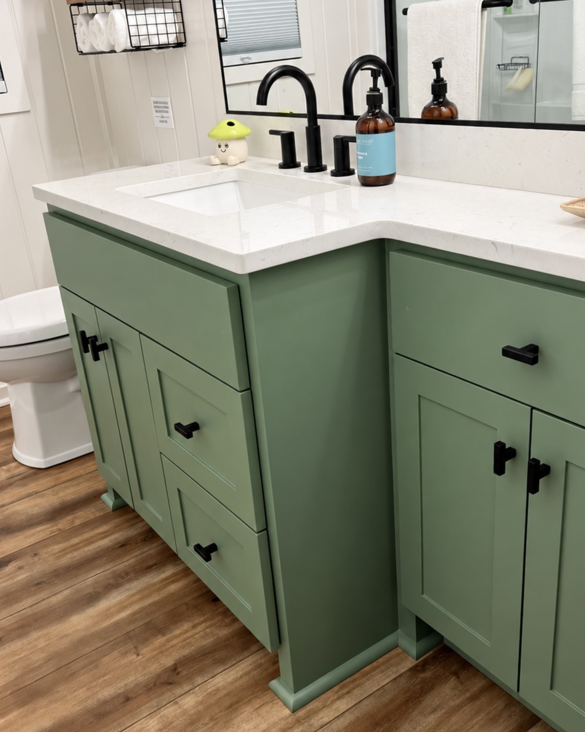 Sage green bathroom vanity with black pulls and a quartz top